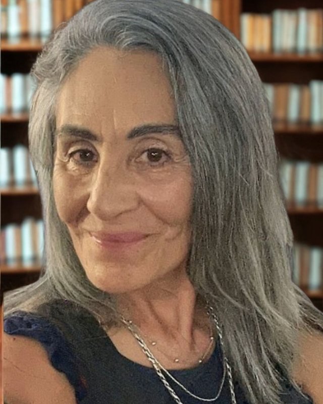 Trinidad Páez sonriendo con calidez frente a una biblioteca de madera.